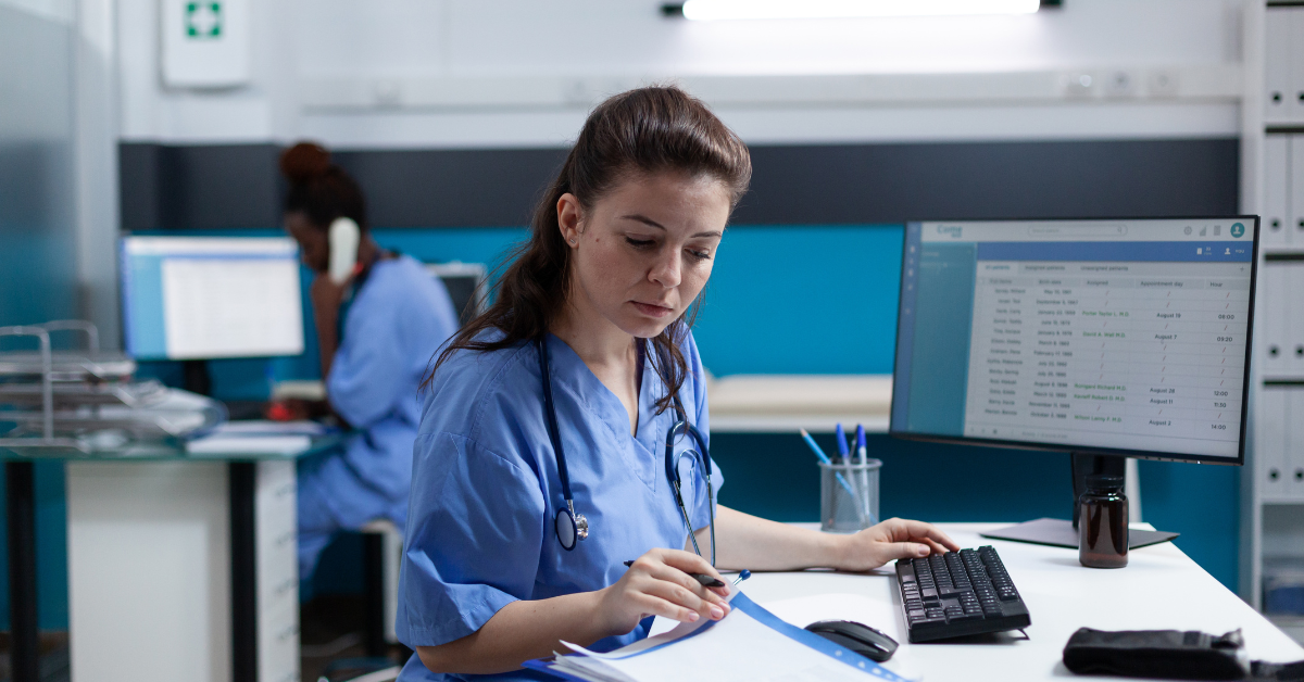 A nurse sits at a desk, reading paperwork. 